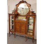 An Edwardian inlaid mahogany mirrored back display cabinet with bowed central compartment over