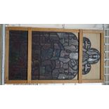 Three Victorian stained glass panels, each depicting a central figure within a shaped border,