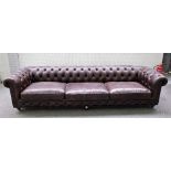 A large brown leather upholstered Chesterfield sofa, on turned supports, 300cm wide x 69cm high.