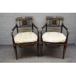 A pair of Regency style parcel gilt ebonised open armchairs on sabre supports,