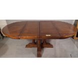 A 20th century oak circular extending dining table, on four turned supports and 'X' frame stretcher,