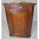 A George III oak hanging corner cupboard, with single panelled door,