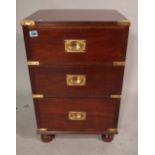 A pair of campaign style brass bound mahogany three drawer pedestals on bun feet,