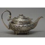 A George IV silver teapot, of compressed oval form, with floral and foliate embossed decoration,