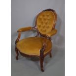 A Victorian mahogany framed open armchair with button back green upholstery on cabriole supports.