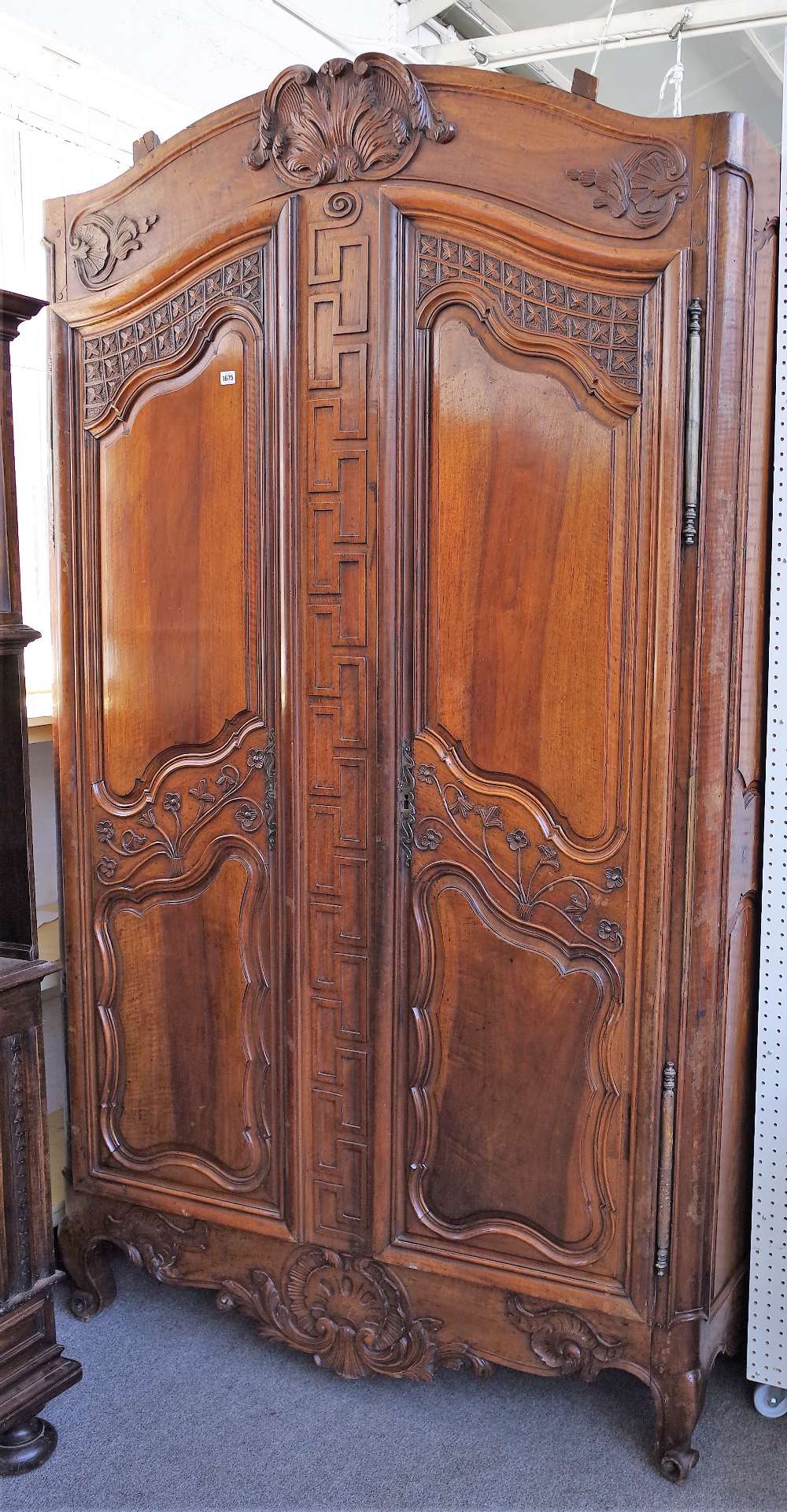 An 18th century fruitwood armoire with carved arched cornice over a pair of shaped panel doors,