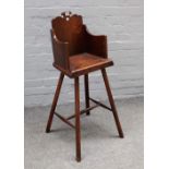 An early 19th century provincial oak child's highchair with solid back and seat on four staked