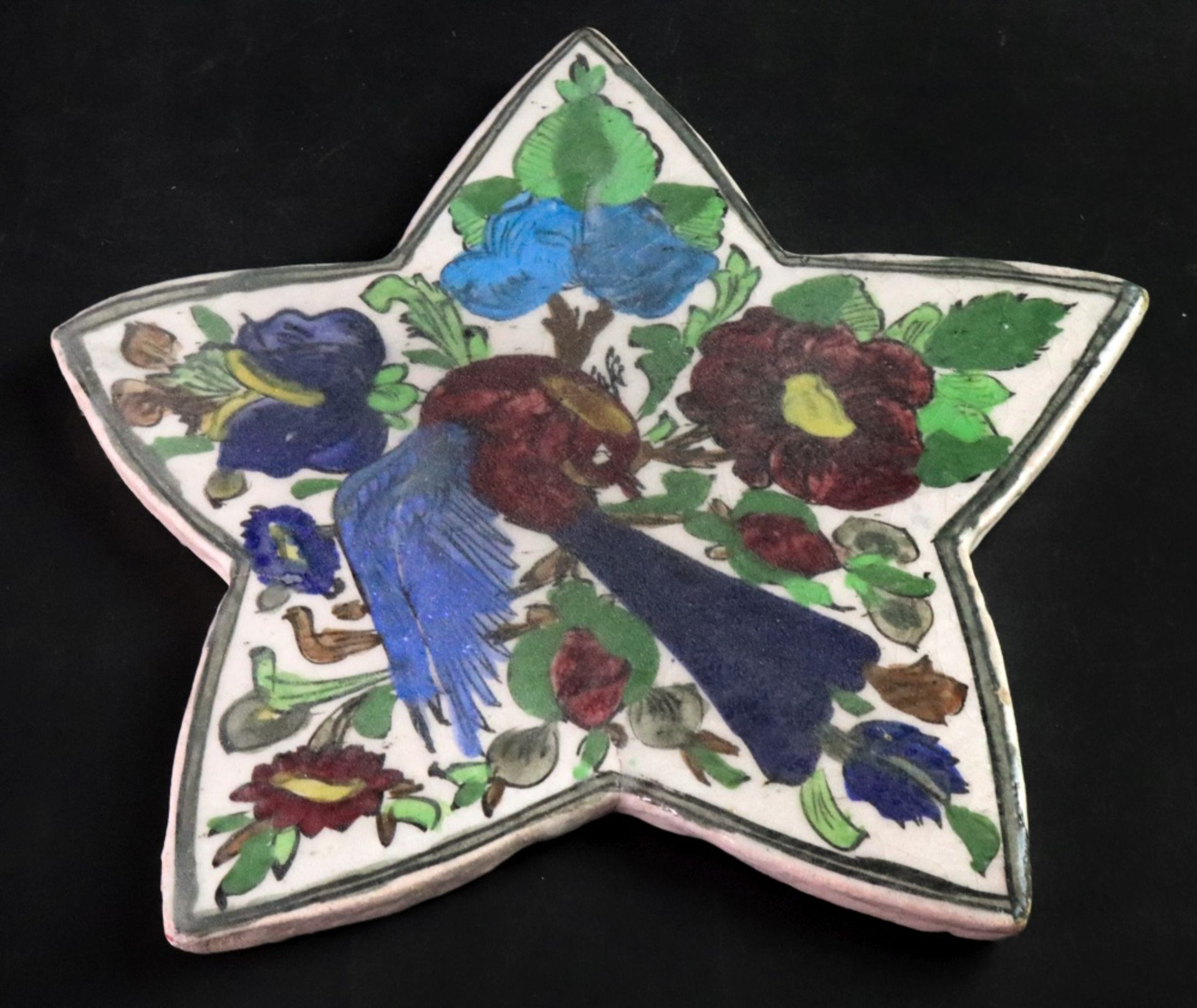 A Qajar star shaped tile, 20th century, painted with a bird and flowering branches, 34 x 32.5cm.