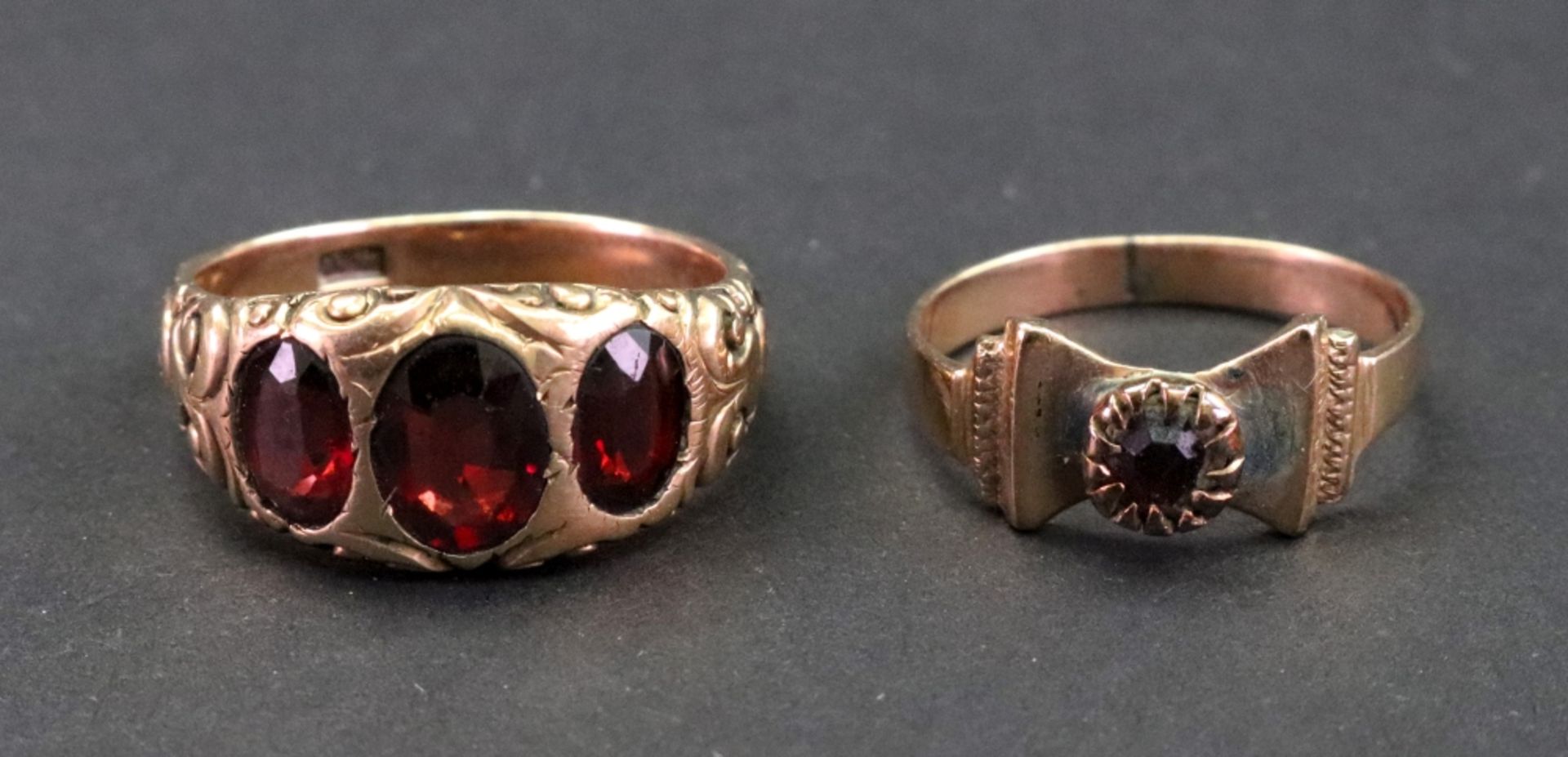 A three stone garnet ring, detailed XV, the oval cut stones to a scroll carved shank, ring size U,