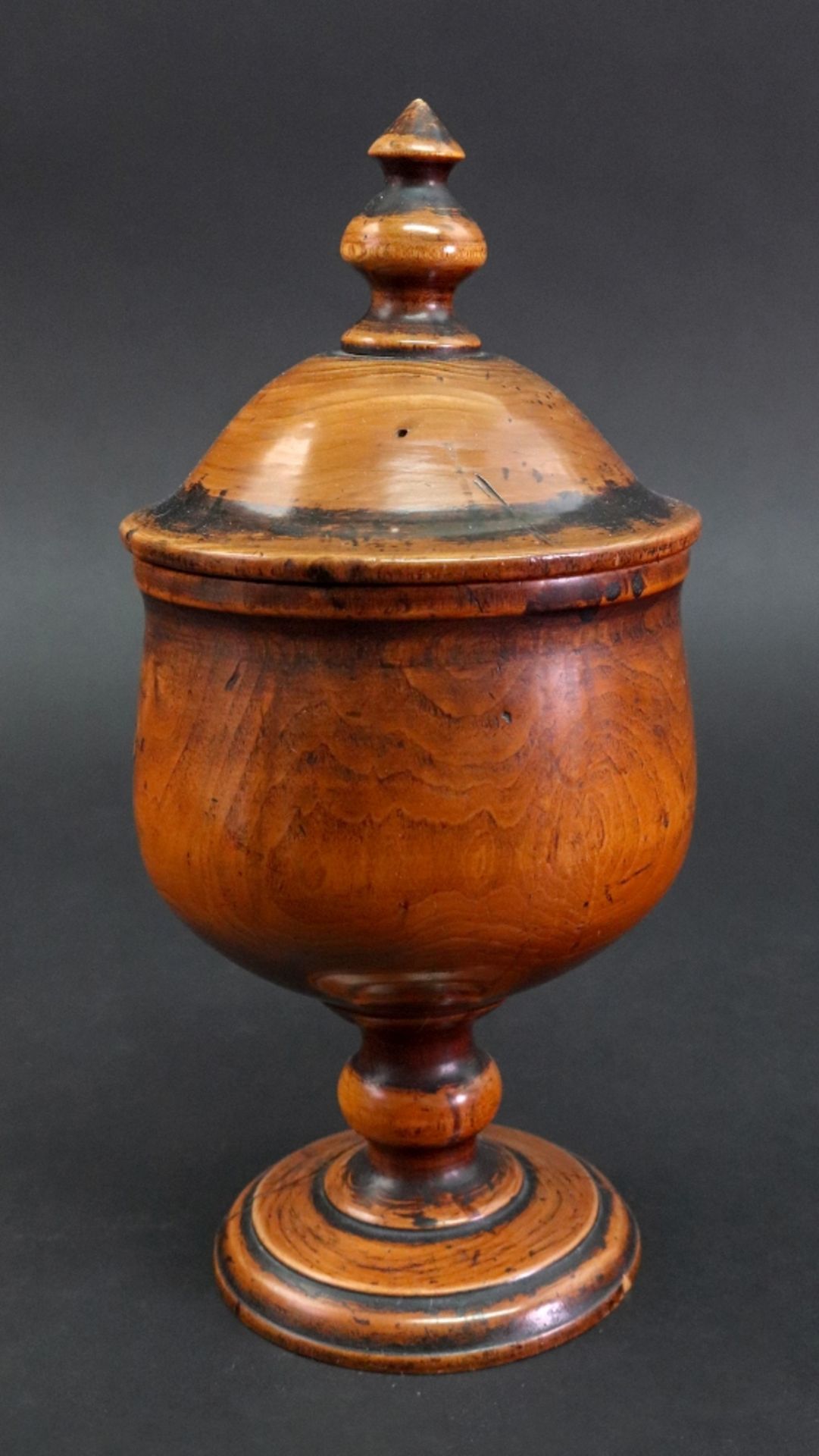 A turned fruitwood cup and cover, 18th century, the domed pull off cover with a turned finial,