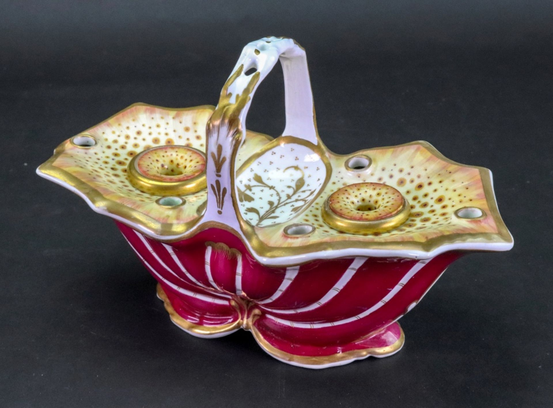 An English porcelain maroon ground inkwell, circa 1820-30, of shell form with overhead handle,