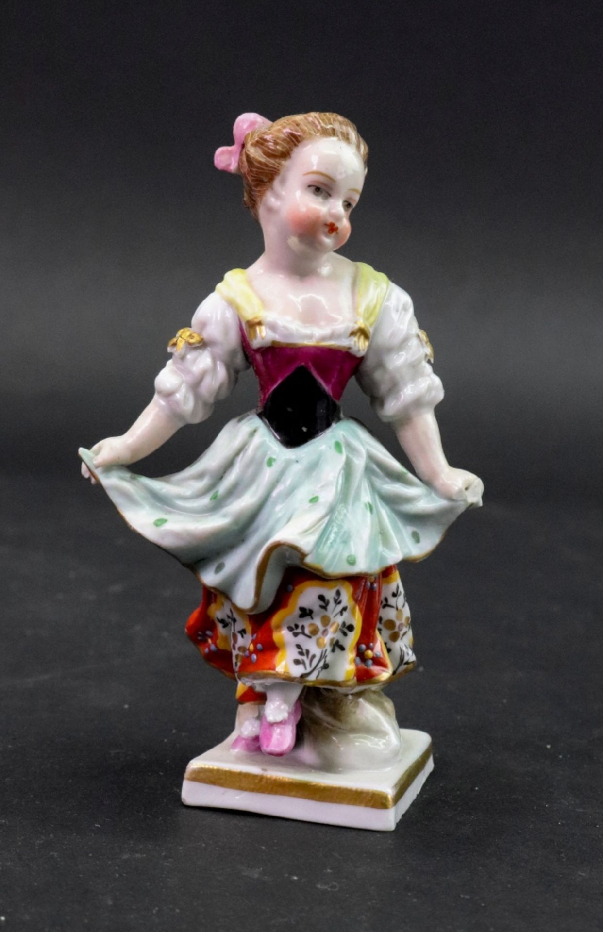 A Sampson porcelain figure of a young girl, her hands gathering up her dress, 11cm high.