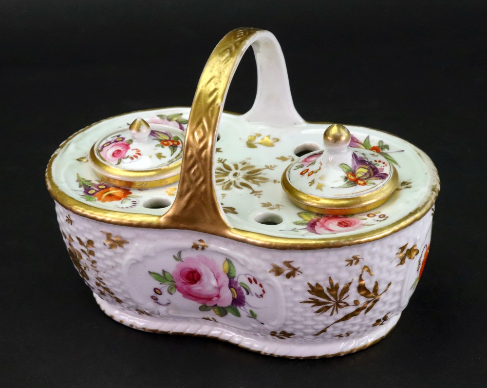 An English porcelain inkwell, circa 1820, of shaped oval form with gilt overhead handle,