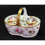An English porcelain inkwell, circa 1820, of shaped oval form with gilt overhead handle,