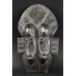 An African tribal wooden carving of two heads side by side, 26.5cm high.