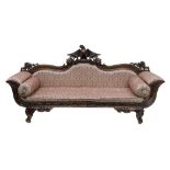 A reproduction Empire style foliate carved mahogany frame settee, with a shaped upholstered back,