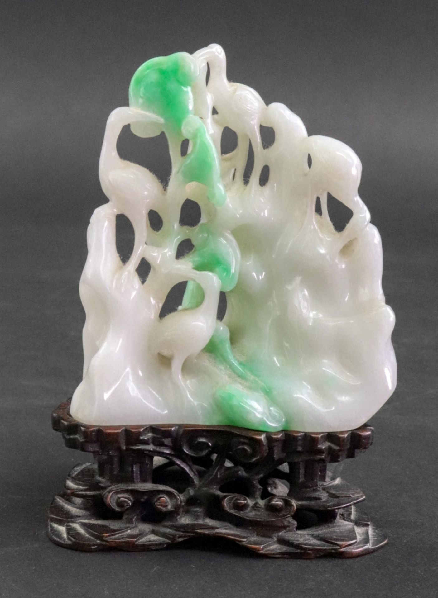 A Chinese jade carving, 20th Century, of four storks amongst trees and rockwork, 8cm high,