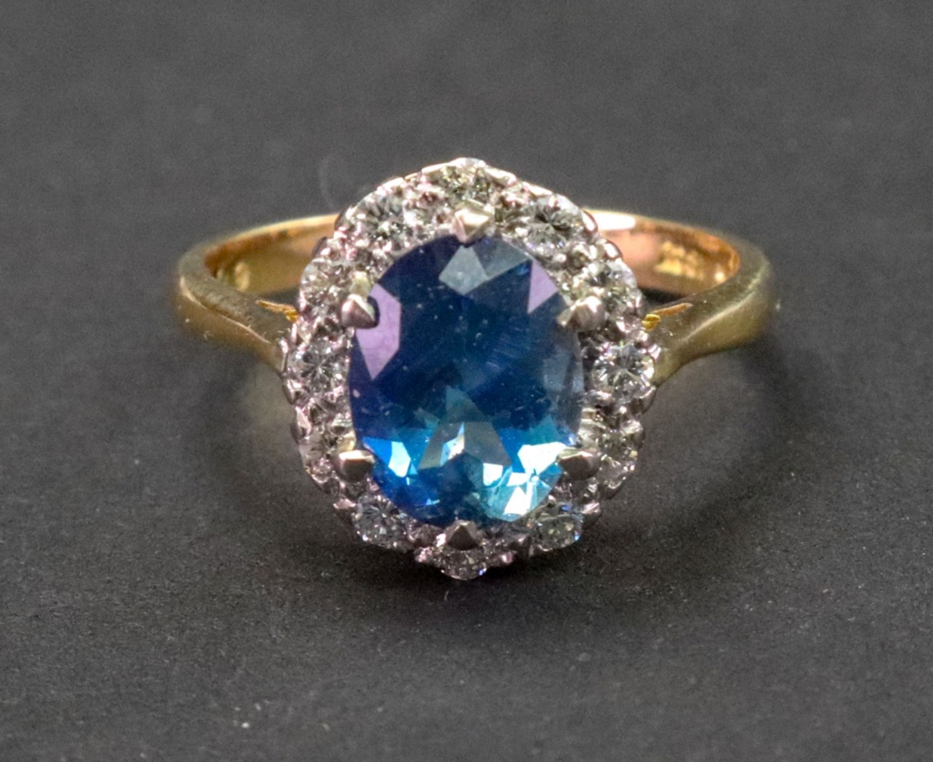 An 18ct gold, aquamarine and diamond cluster ring, the oval cut aquamarine six claw set,