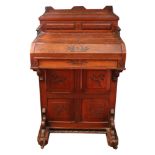 A late Victorian foliate carved walnut piano front davenport, of panelled construction,