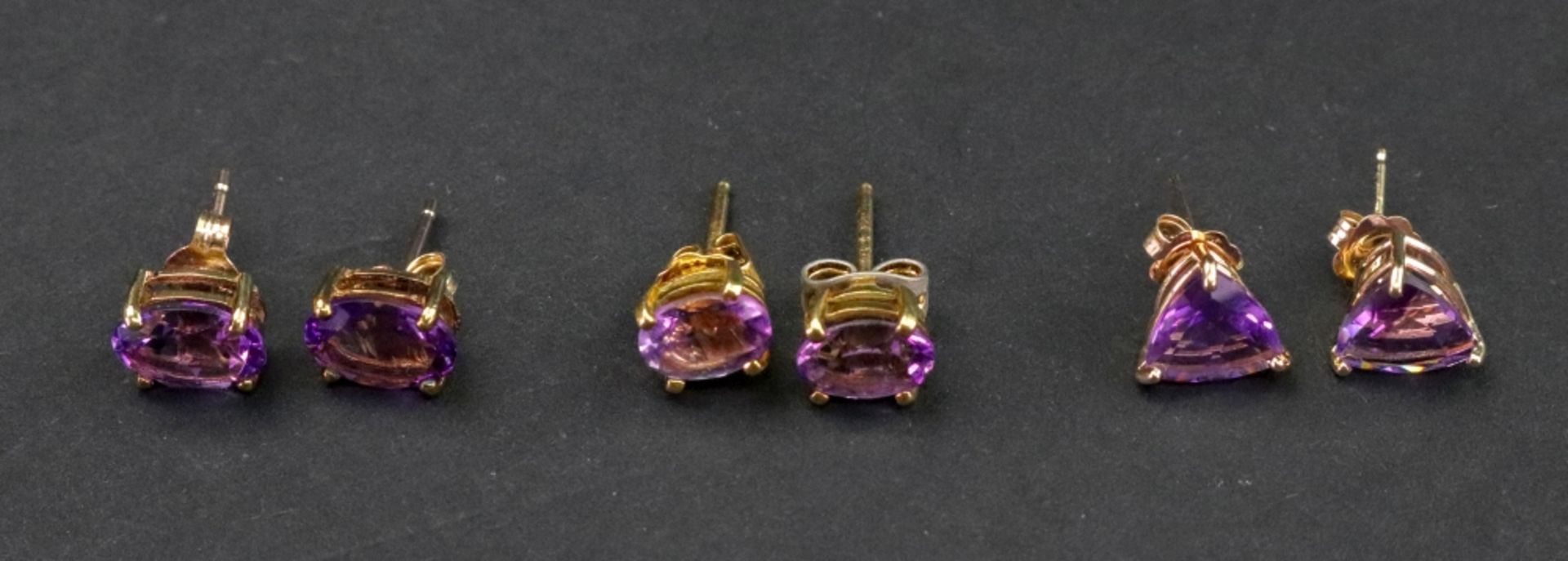 Three pairs of amethyst set earstuds, set variously with oval and triangular cut stones.