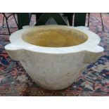 A large limestone mortar of circular tapering from with four lugs to the outer rim,