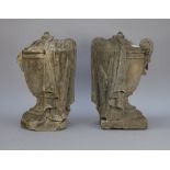 A pair of stone urns and covers, each partially draped in cloth over a square foot, (a.f.