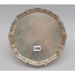 A silver salver, of shaped circular form, having a shaped pie-crust rim with a gadrooned border,