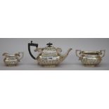 A late Victorian silver three piece tea set, comprising; a teapot, having black fittings,