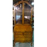 A Queen Anne style figured walnut bureau bookcase, on shell capped cabriole supports,