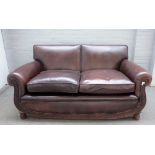 A 20th century brown leather sofa with grape and vine carved oak frieze, on melon feet,