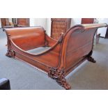 A hardwood sleigh bed, each scroll end with carved rococo revival decoration, on lions paw feet,
