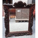 A Chinese hardwood mirror with extensively carved frame depicting hunting scenes,