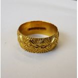 A 22ct gold wide band wedding ring, with facet cast decoration, London 1973, ring size Q