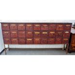 A stained pine apothecary cabinet with three rows of nine drawers, on metal stand,