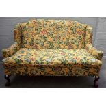 A George II style stained beech floral upholstered wingback sofa, on claw and ball feet,