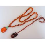 An Asian amber and jade pendant necklace, the front with an oval amber drop, with a jade surmount,