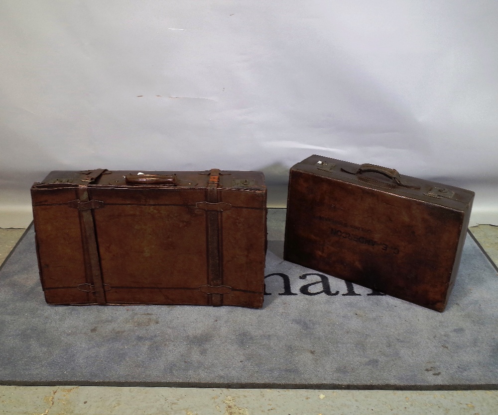 An early 20th century leather suitcase, 80cm wide x 23cm high, and another smaller,