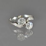 A diamond two stone ring, claw set with the two principal cushion shaped diamonds to the centre,