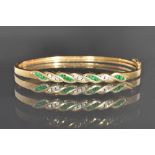 A gold, emerald and diamond set oval hinged bangle,