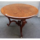 A Victorian figured walnut circular table on three scroll supports, united by shaped stretcher,