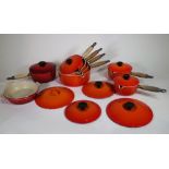 Six Le Creuset volcanic orange saucepans with lids, sizes 22, 20,18,16,16,14, another saucepan,