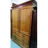 A late Victorian faded walnut linen press with cupboard doors over two short and two long drawers