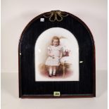 A mid-20th century German painted porcelain plaque of a girl within a mahogany arch top frame,