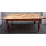 A stained pine kitchen table, the pegged biscuit joint plank top on tapering square supports,