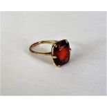 A gold and hessonite garnet single stone ring, claw set with a cushion shaped hessonite garnet,