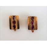 A pair of gold, magenta sapphire and red gem set three stone earclips,