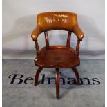 A late 19th century office armchair with elm slab seat and tan studded leather upholstery.