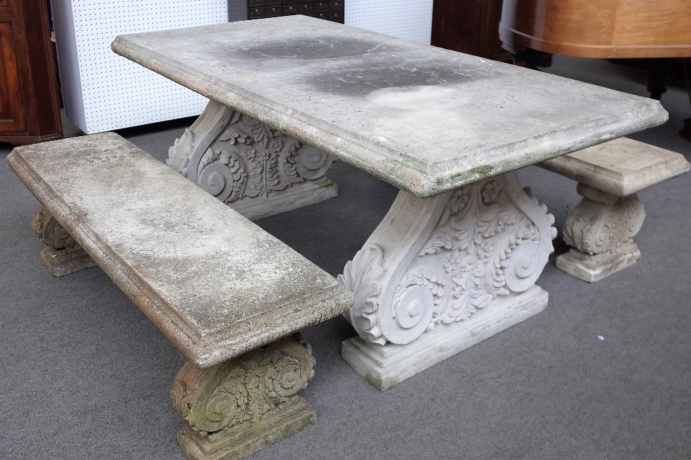 A faux stone rectangular garden table on a pair of acanthus scrolling trestle supports,