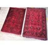 Two similar Afghan Beluche rugs, each with madder fields, one with two square sections,