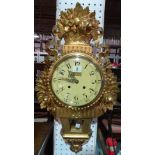 An early 20th century gilt painted eight day wall clock, with floral moulded decoration, 40cm high.